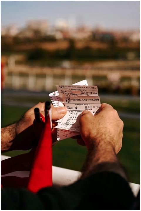Close-up of a man holding horse racing tickets in
