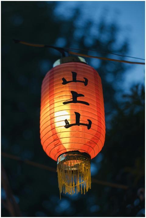 A glowing red Chinese lantern hanging outdoors at