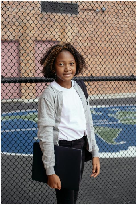 Happy girl standing outdoors with a laptop by a sp