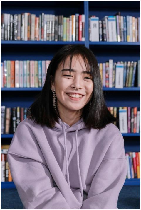 Happy teen girl in a purple hoodie sitting in a li