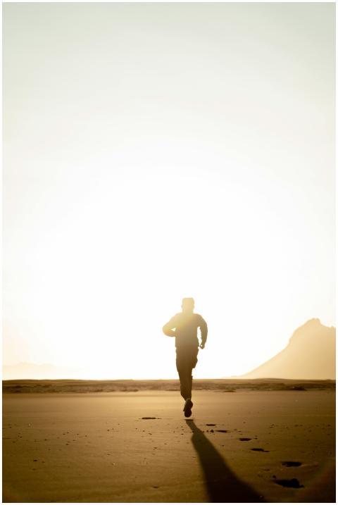 Silhouette of an adult running on the beach during