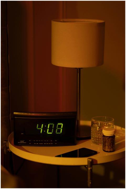 A warm and moody bedside table with a digital cloc