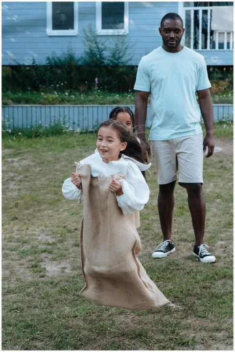 A young girl enjoys a sack race outdoors while a f