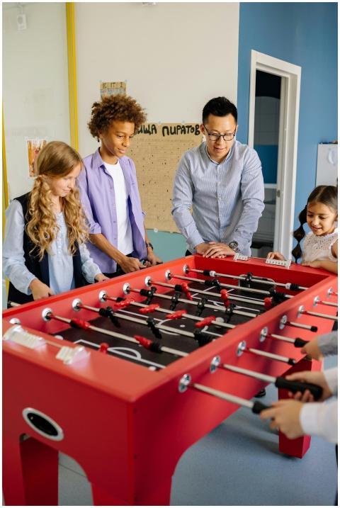 Teacher and students enjoying a foosball game in a