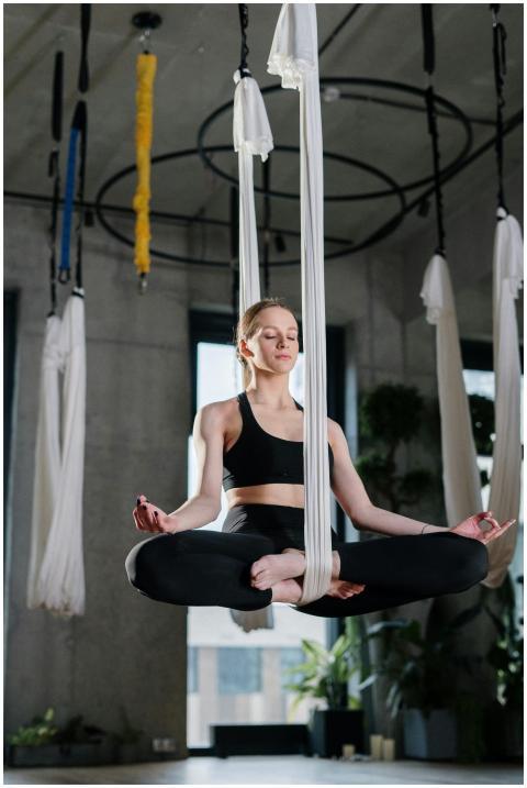 Woman practices aerial yoga in a modern studio, ac