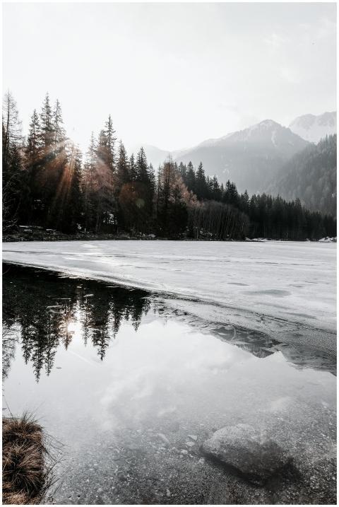 A serene frozen lake reflecting snow-capped mounta