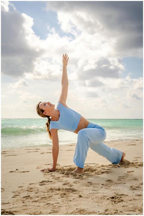 A woman performs a yoga pose on a sunny beach, und