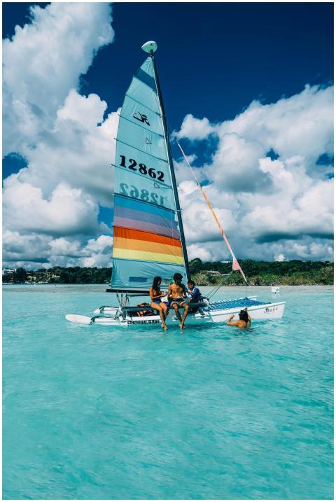 A colorful sailboat with people enjoying a sunny d