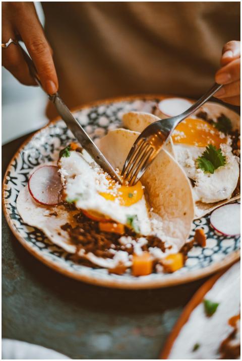 Close-up of hands cutting into a taco with fried e