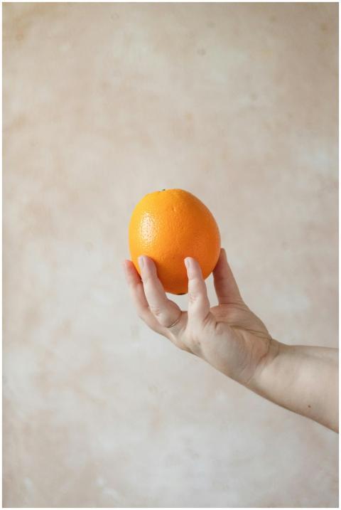 Close-up of a hand holding a vibrant orange fruit