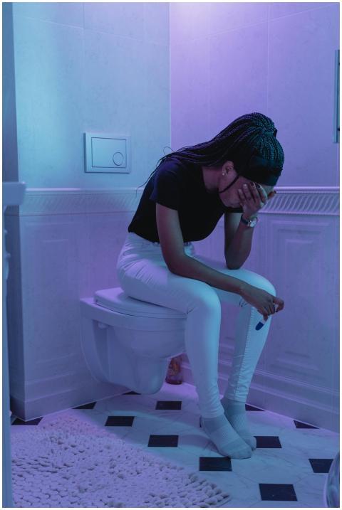 A concerned woman sitting on a toilet holding a pr