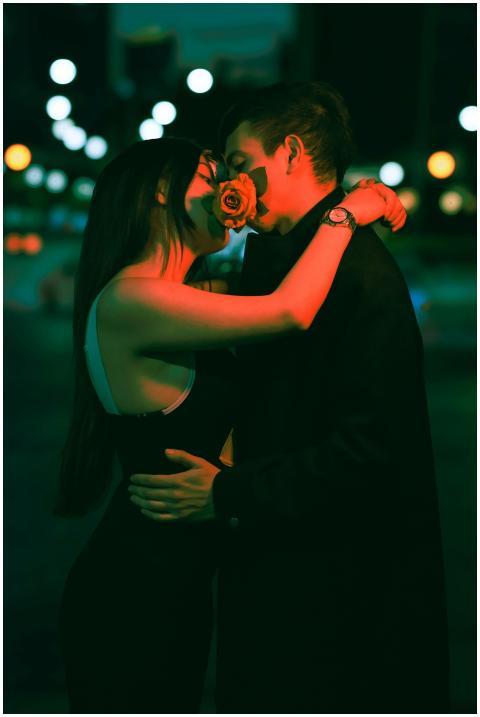 A couple shares a romantic moment with a rose in a