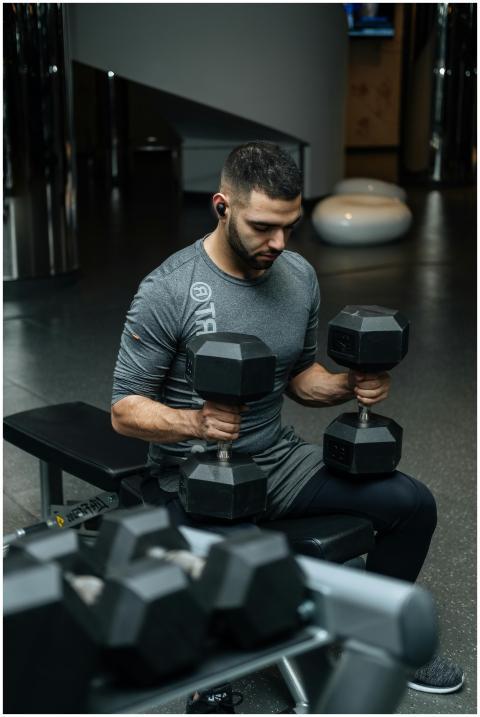 Adult man lifting dumbbells in a gym, focused on s