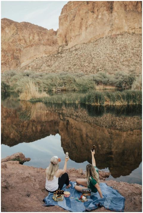 Two women enjoying a picnic by a serene lake with