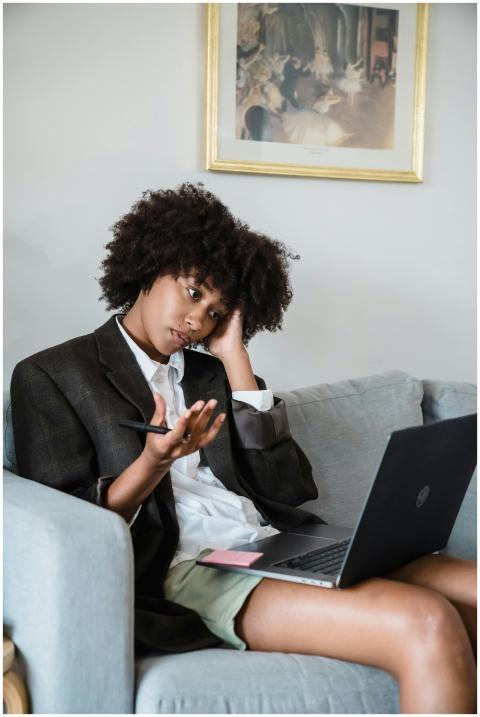 A woman in casual attire sitting on a couch, looki