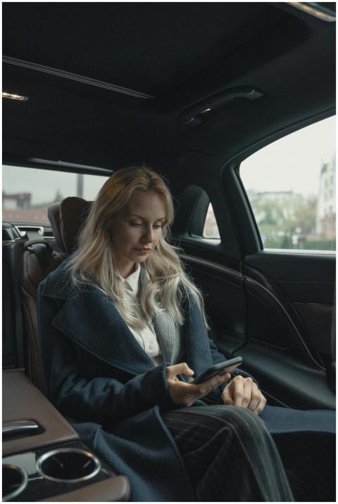Professional woman in luxury car using smartphone,