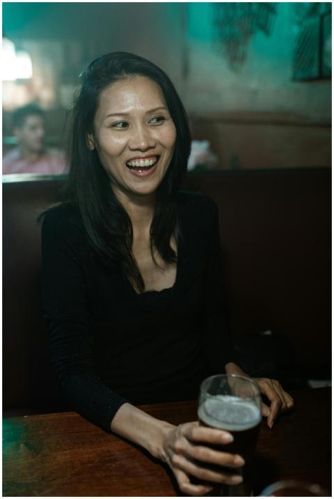 A cheerful woman enjoying drinks at a cozy lounge,