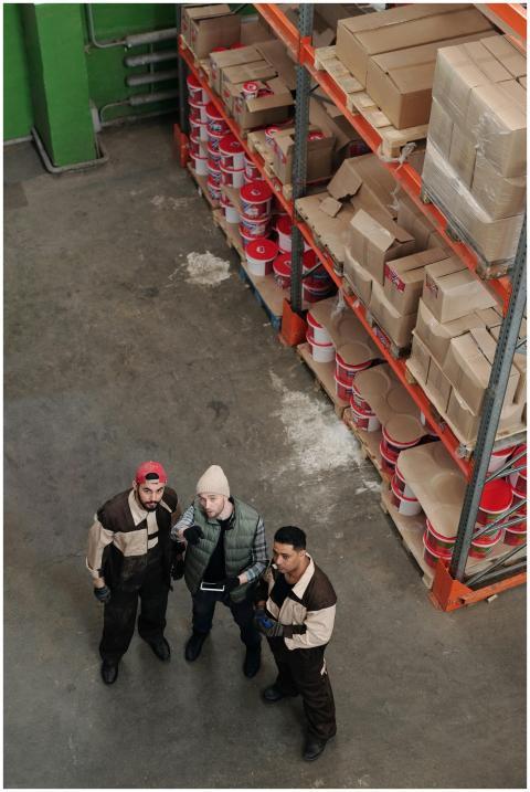 Workers in a warehouse discussing logistics near s