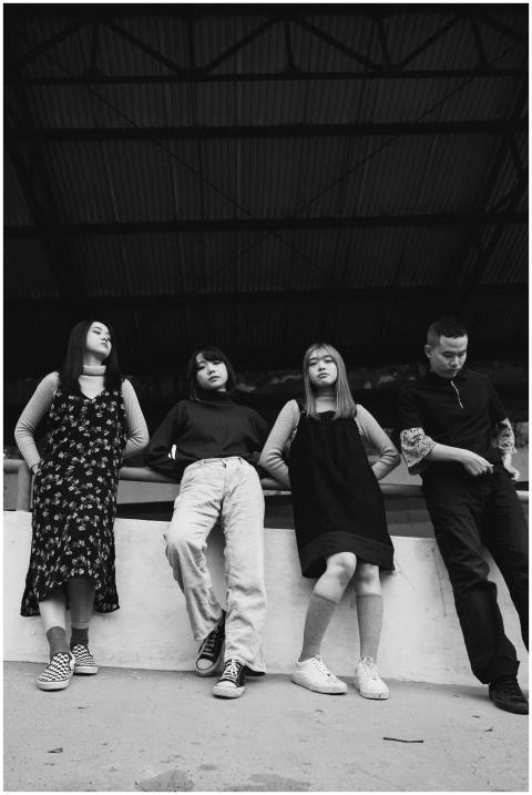 Black and white image of four young adults posing
