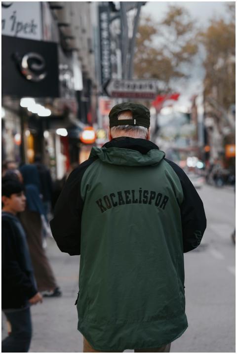 A man wearing a Kocaelispor jacket stands on a bus