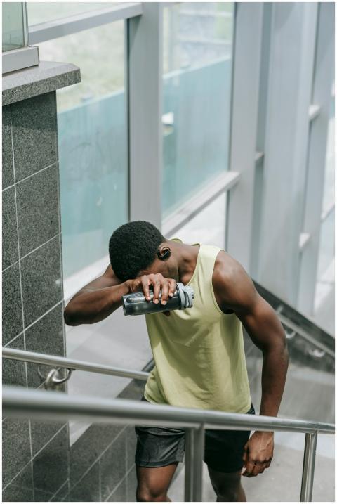 A fit man in sportswear pauses on stairs, holding