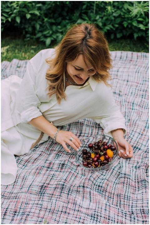 Woman relaxing on a picnic blanket with a bowl of