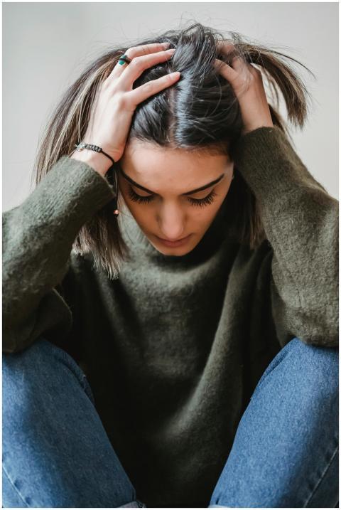 A woman sitting indoors, appearing stressed or ups