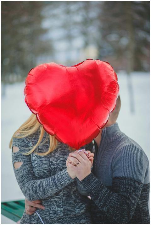 A couple embraces behind a heart-shaped balloon ou