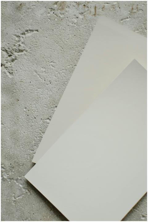 Two blank papers placed diagonally on a textured c
