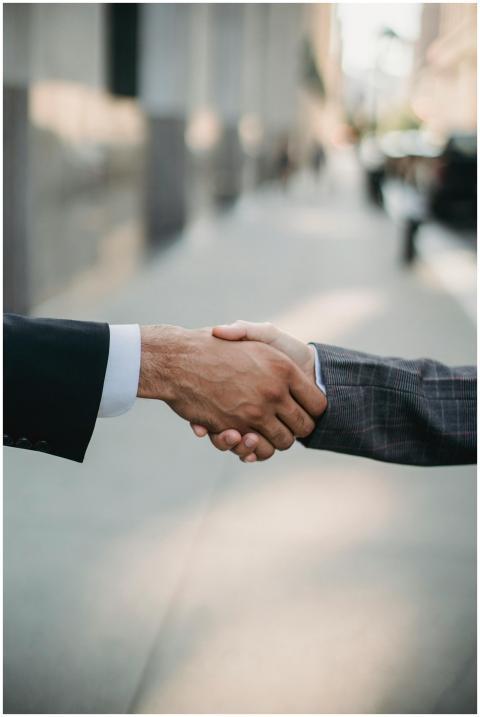 Two businessmen shaking hands outside, symbolizing