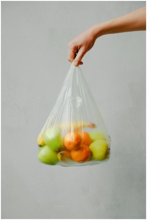 A hand holding a transparent plastic bag full of f