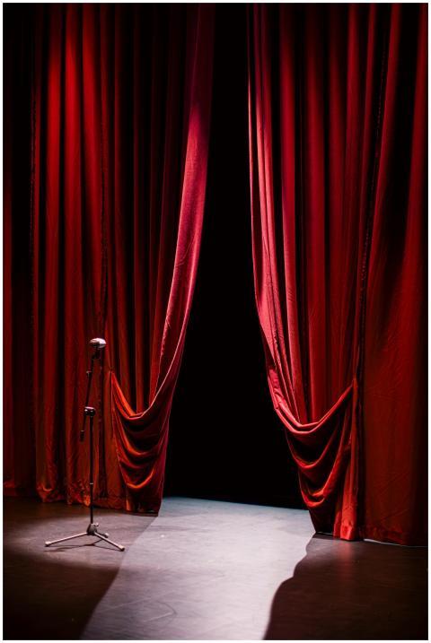 A theater stage with closed red curtains and a sin