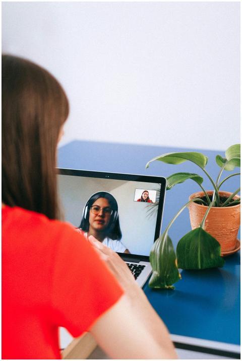 Woman in red shirt video chatting on laptop with p
