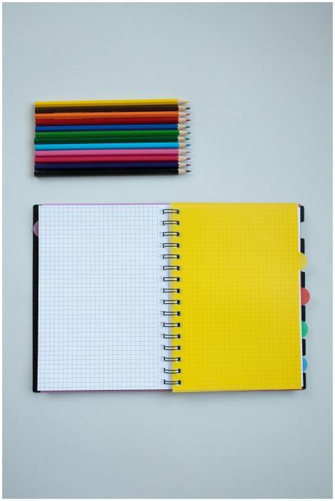 Colorful pencils and a spiral notebook on a white
