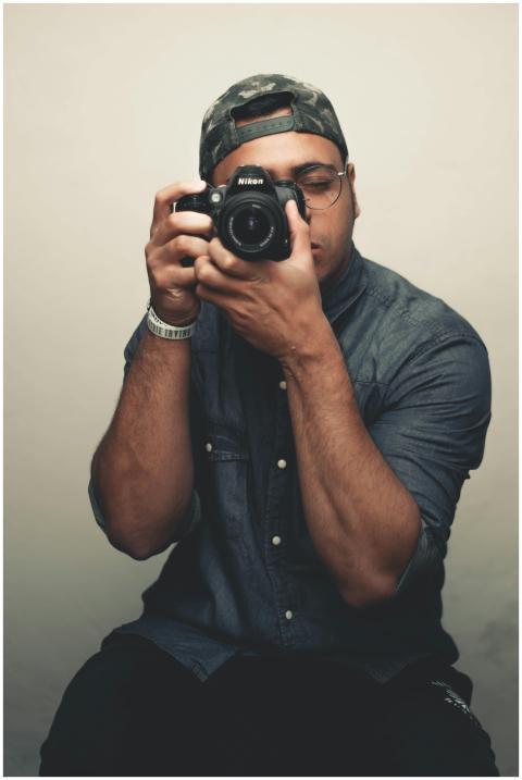 A fashionable male photographer shoots with a DSLR