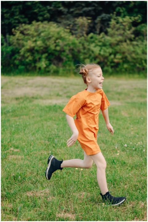 A happy child running in a green field wearing an