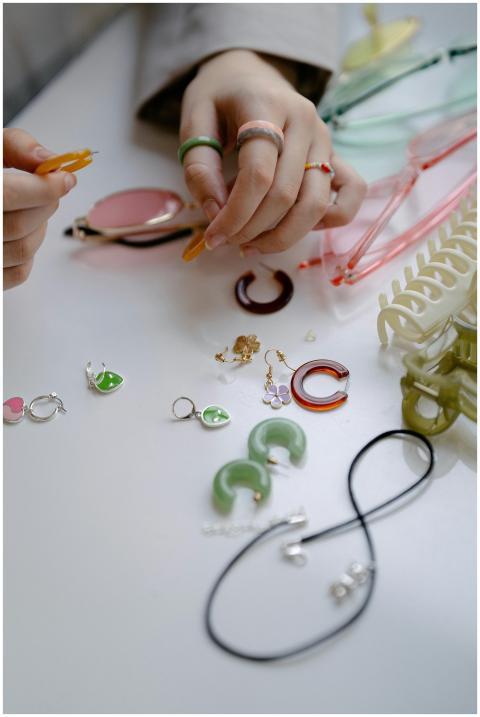Hands arranging colorful jewelry and accessories o