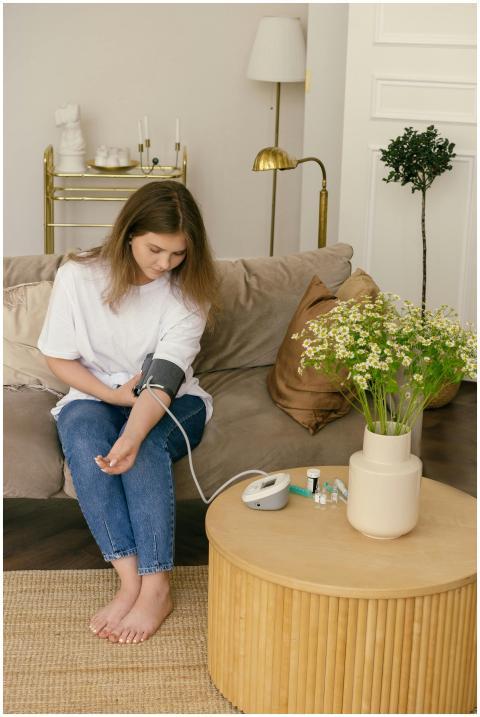 Woman sitting on couch using blood pressure monito