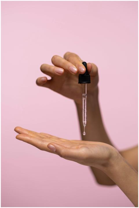 Close-up of hands with dropper applying face serum