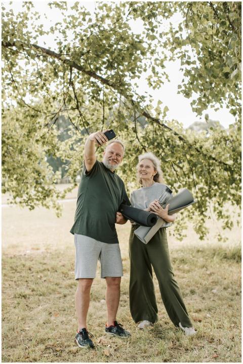 Elderly couple taking a selfie in a park, holding