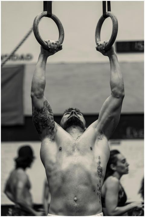 Muscular man shows strength during ring exercise i