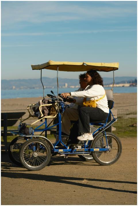 A couple enjoys a sunny ride on a pedal car by the