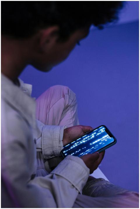 Teenager casually browsing on smartphone indoors,
