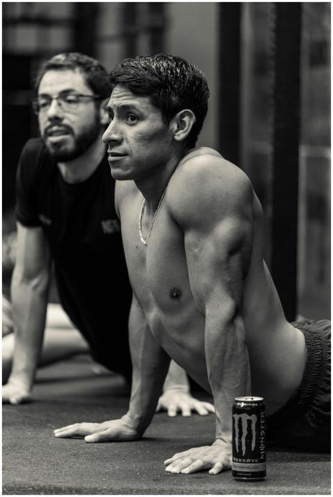 Two men performing yoga exercises in a gym setting