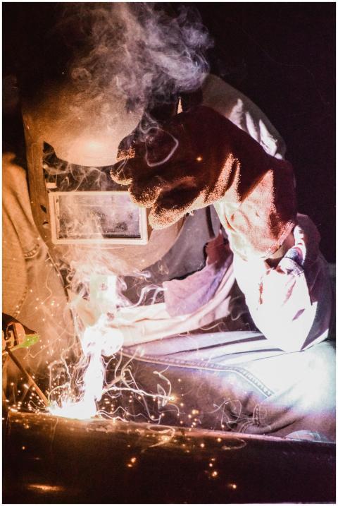 A welder in protective gear works with intense spa
