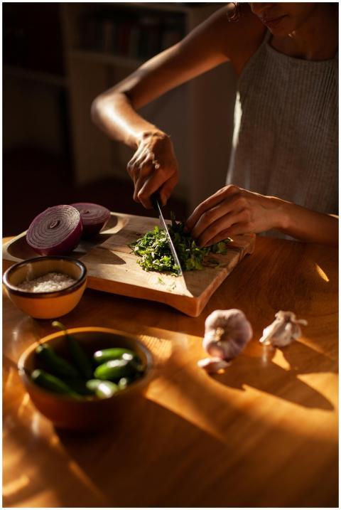 A person chopping cilantro with fresh ingredients