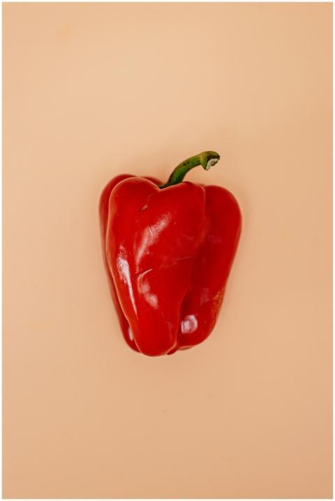 A vibrant red bell pepper placed against a muted b