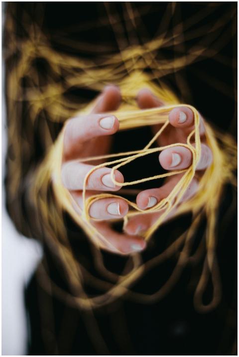 Close-up of hands intricately tangled in yellow st