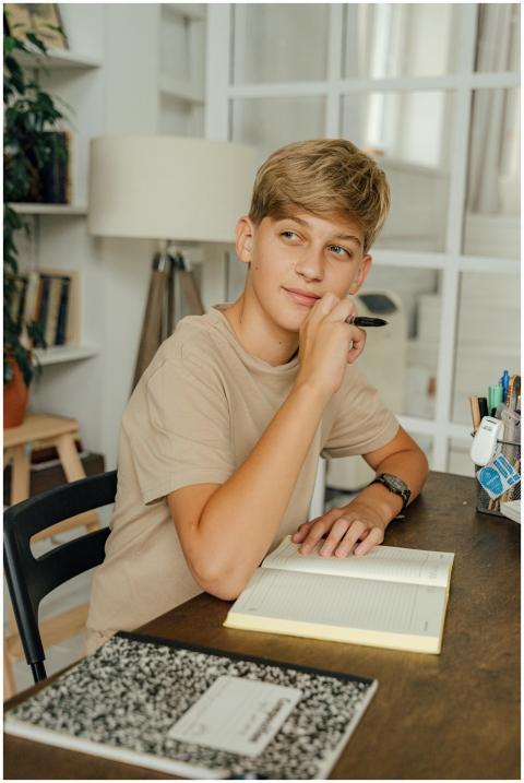 A child with blonde hair pens thoughts in a notebo