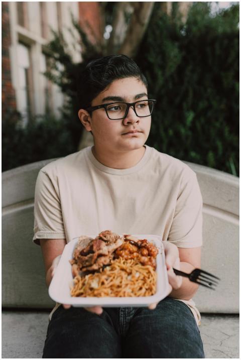 Young teen holding an appetizing plate of Asian fo